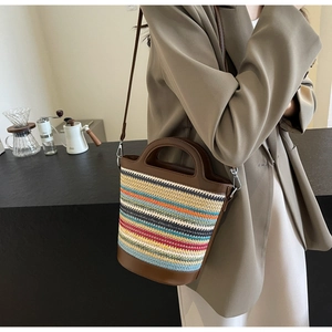 Detail of multi-colored knitted straw bucket bag with leather trim on coffee bar counter