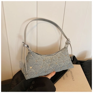 Blue denim crossbody bag with quilted stitching and rhinestones shown on model