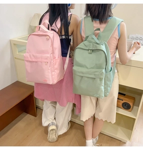 Dettaglio degli zaini in nylon rosa e verde che mostra le tasche laterali porta borraccia