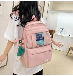 Sac à dos en nylon rose avec plusieurs compartiments zippés et un porte-clé en peluche vert