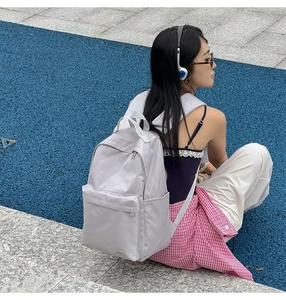 Dettaglio ravvicinato dello zaino in nylon lilla con design multitasche su pista blu