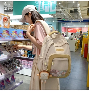 Close-up of beige nylon backpack with mesh pockets and cute plush charm in a shop
