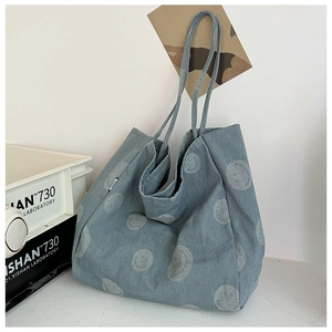 Macro detail of casual denim tote bag featuring gray smiley faces and soft shoulder straps