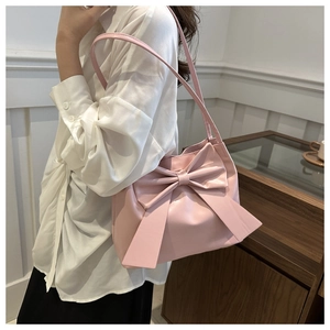 Detail of a sweet pink PU shoulder bag featuring a large decorative bow on the front