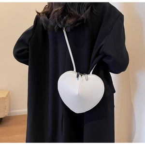 Vista posteriore di una borsa a tracolla bianca a forma di cuore su un cappotto nero