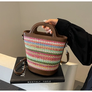 Colorful woven straw bucket bag with brown leather trim and adjustable shoulder strap