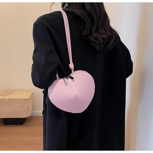 Dettaglio di una borsa a spalla rosa a forma di cuore con doppia cerniera in argento e nodi