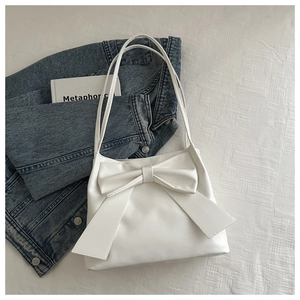 Minimalist white PU leather shoulder bag with a large decorative bow on a textured background