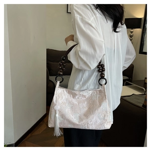 Detail of fabric handbag with wooden bead handle and long tassel in chic style