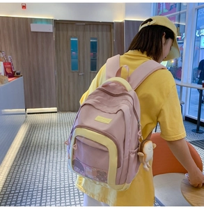 Detailed back view of pink and yellow nylon backpack with mesh pocket and plush charm