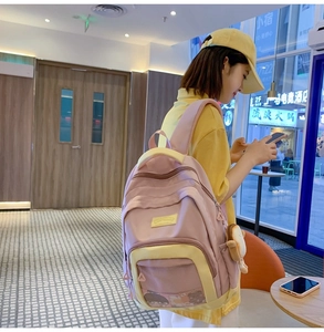Detail of pink and cream nylon backpack featuring multiple pockets and a plush bread charm