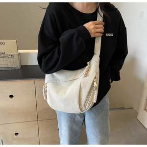 Close-up of beige corduroy crossbody bag with vertical texture and woven zipper detail