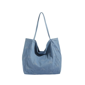 Blue denim tote bag with white bow pattern and long shoulder straps for women