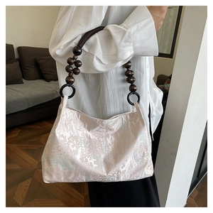 Detailed texture of champagne jacquard satin fabric and vintage wood bead handle on bag