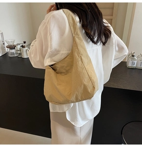 Vista detallada del bolso tote de nailon caqui en modelo en ambiente de cafetería