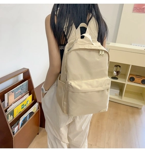 Dettaglio di uno zaino in nylon beige con tasche laterali e ampia tasca anteriore