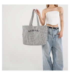 Close-up of black and white striped canvas tote bag with summer embroidery detail
