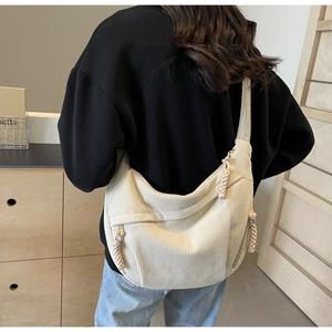 Detail of off-white corduroy crossbody crescent bag with woven zipper puller