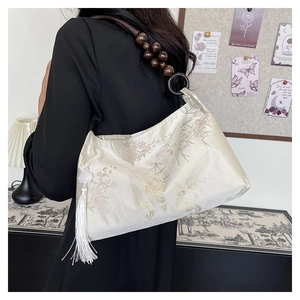 Detail of vintage beige satin underarm bag with floral pattern and wooden bead strap