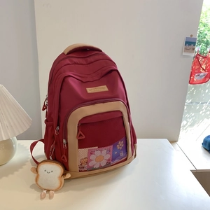 Detail of burgundy nylon crossbody bag with khaki handles and cute bread plush charm