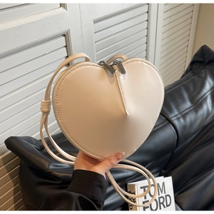Dettaglio della borsa a tracolla crema a forma di cuore con cuciture a V e cinturino