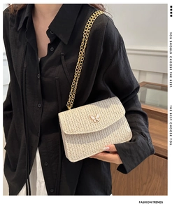 Detail shot of the woven straw crossbody bag with gold chain strap on a model