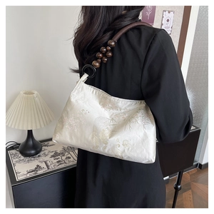 Detailed texture of fabric handbag with jacquard floral pattern and wooden bead strap