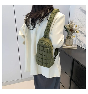 Rear view of model wearing a military green quilted nylon crossbody bag with wide strap