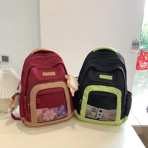 Detail of nylon backpacks with mesh pockets, floral patches, and bread plush pendant