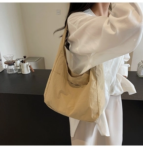 Detalle del bolso tote de nailon caqui con bolsillos delanteros en el hombro de una modelo