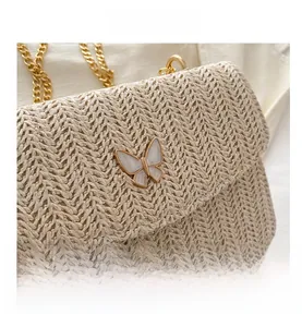 Detail of woven fabric texture and gold butterfly clasp on beige crossbody bag