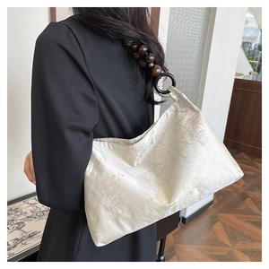 Detail of off-white silk shoulder bag with bamboo embroidery and wooden bead strap