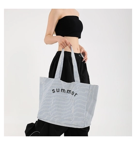 Detail view of large blue and white striped tote bag with summer text on the front pocket