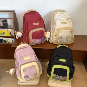 Detail of colorful nylon backpacks in burgundy and cream with cute toast plush pendants