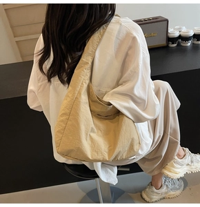 Vista trasera de una modelo con un bolso de hombro grande de nailon beige en un café