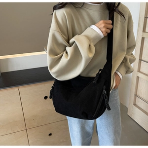 Detail of black corduroy crescent bag with rope zipper worn by model in minimalist setting
