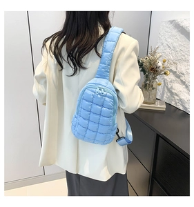 Detail view of the quilted pattern and wide strap on the light blue nylon crossbody bag