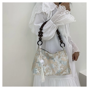 Detail of floral brocade shoulder bag with wooden bead strap and white tassel charm