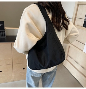 Bolso tote negro de nailon con correa ancha mostrado en modelo para uso diario casual