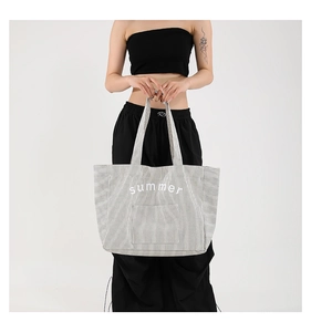 Detail of striped canvas tote bag featuring 'summer' text and a large front pocket