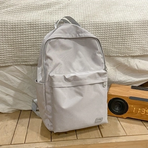 Zaino in nylon grigio minimalista con tasca frontale con zip su pavimento in legno