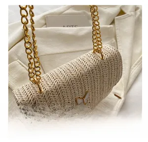 Close-up of woven cream crossbody bag with gold chain strap and butterfly clasp detail