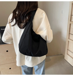 Vista trasera de un bolso bandolera grande tipo media luna negro minimalista en modelo