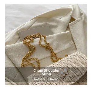 Detail of woven cream crossbody bag with gold chain strap and butterfly clasp decor