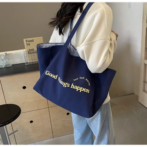 Detail view of navy blue canvas tote bag featuring yellow typography and striped lining