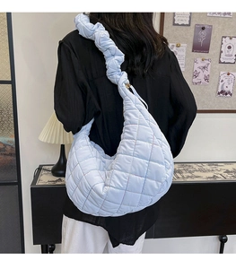 Detail of light blue quilted nylon shoulder bag with cloud-style pleated wide strap