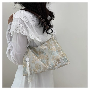 Detail of jacquard brocade bag featuring landscape pattern, wood bead strap and tassel