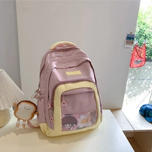 Pink and yellow nylon backpack with mesh front pocket and cute plush charm on a desk