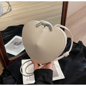 Dettaglio di una borsa a tracolla in pelle a forma di cuore bianco crema con doppia cerniera