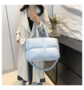 Quilted light blue nylon tote bag worn with a chic trench coat for urban style